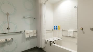 A modern bathroom with a shower, grab bars, a towel rack, and a toilet paper holder.