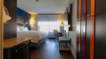 Habitación de hotel con cama, escritorio, silla y televisor.