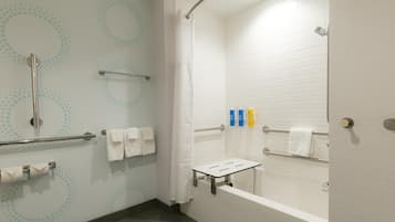 A modern bathroom with a shower, grab bars, a towel rack, and a toilet paper holder.