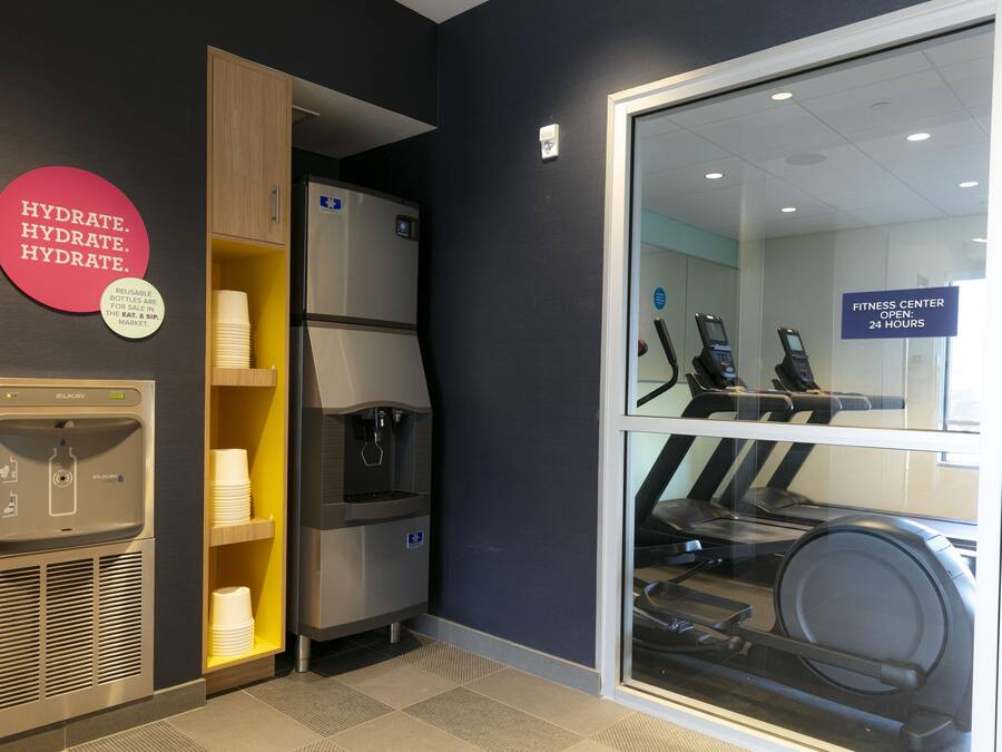 Un gimnasio con dispensador de agua, refrigerador y equipo de ejercicio.
