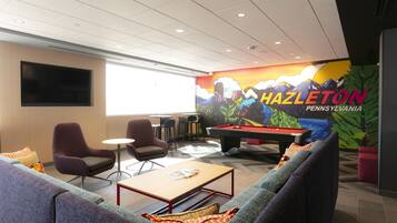 A lounge area with a pool table, comfortable seating, and a mural of HAZLETON PENNSYLVANIA.