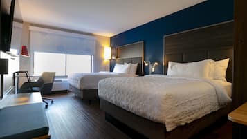 Quarto de hotel com duas camas, uma escrivaninha, uma cadeira e uma televisão.