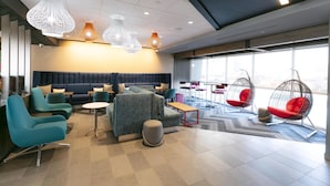 A modern lounge area with seating, pendant lighting, and large windows. - Tru By Hilton Hazleton (Hazleton)