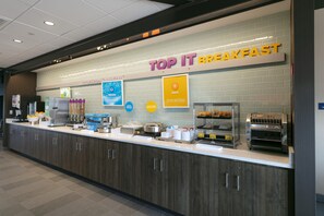 A breakfast counter with a sign reading 'TOP IT BREAKFAST,' various food items, and kitchen appliances.