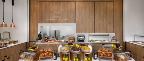 A breakfast buffet with various food items and a wooden wall with a logo.