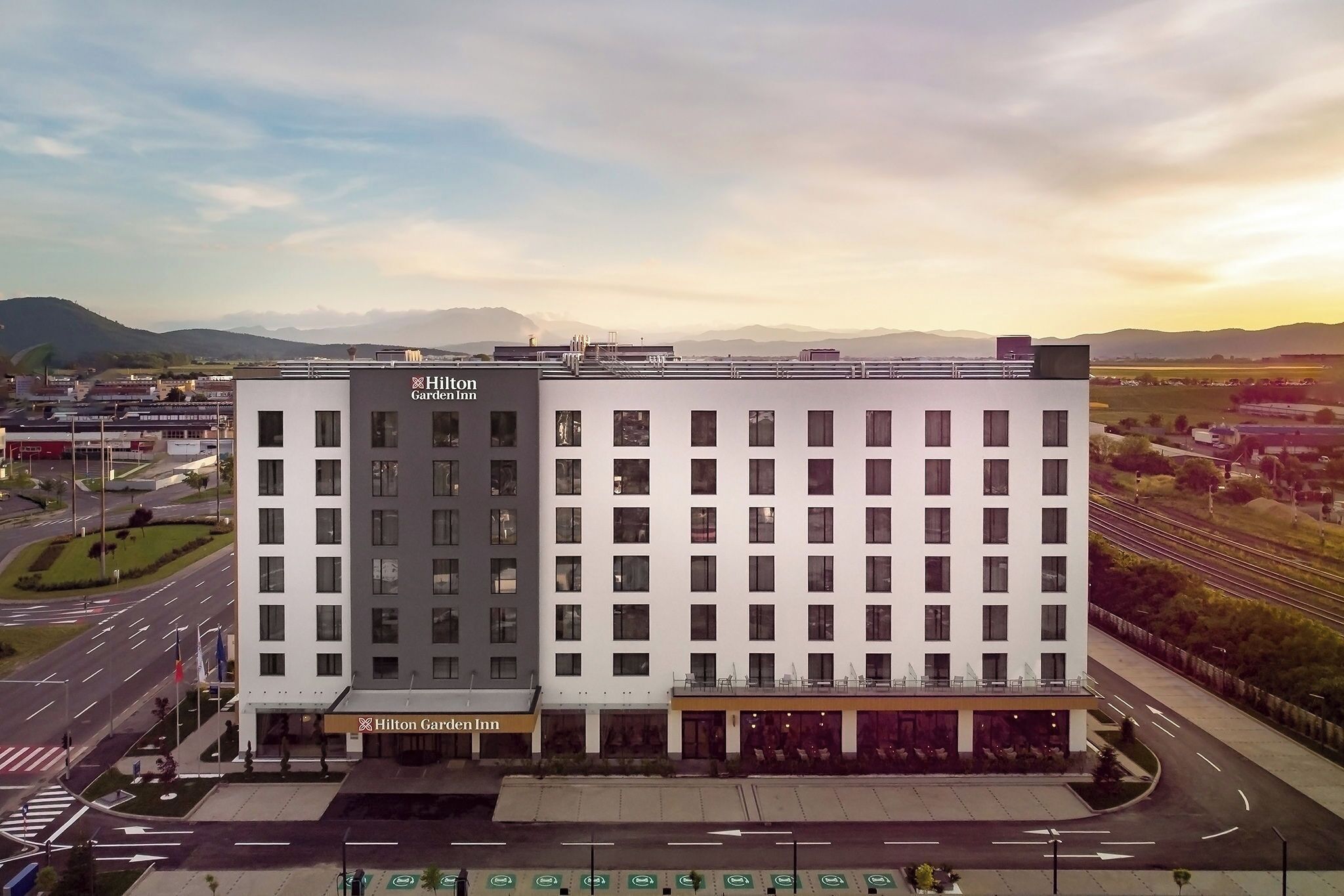 Un hotel moderno con un letrero llamativo, varios pisos y un estacionamiento.
