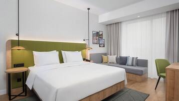 Una habitación de hotel con una cama grande, un sofá, un escritorio y una silla.