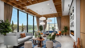 A modern living room with a sofa, ottomans, a coffee table, and a fireplace. - Hilton Garden Inn Brasov (Brasov)