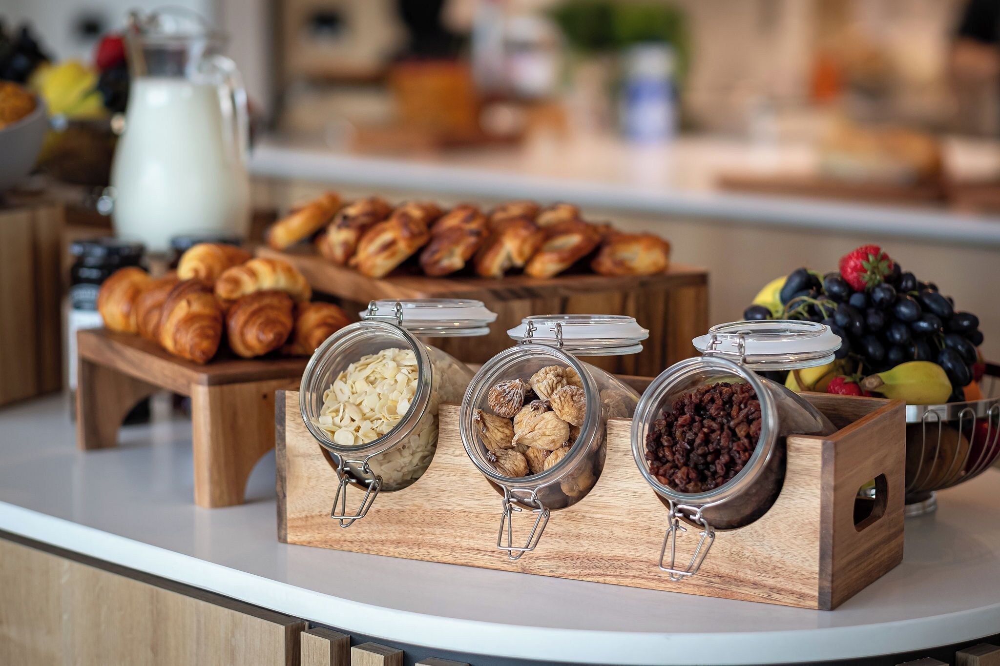 Um buffet de café da manhã com pães, frutas e oleaginosas.