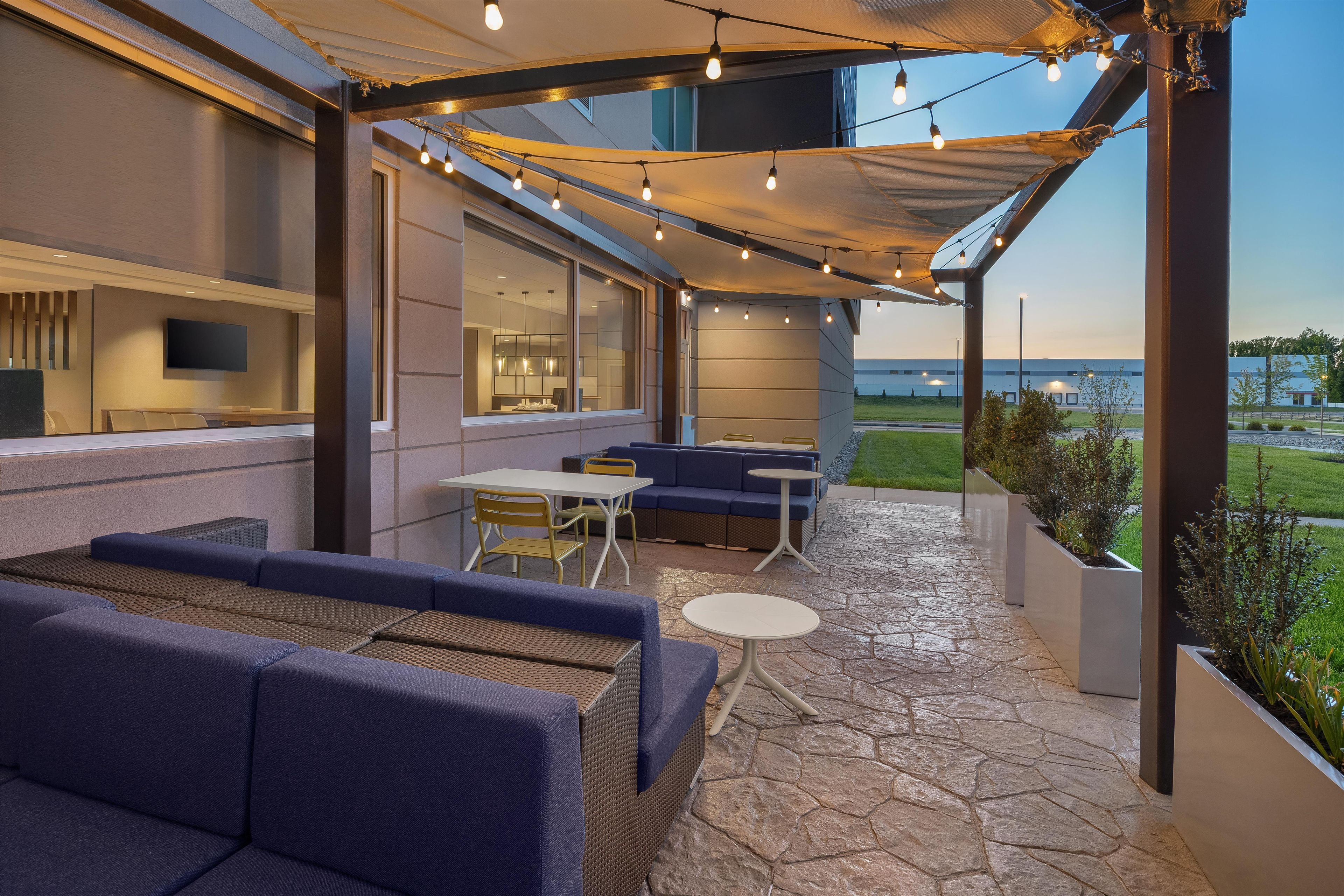 An outdoor patio with seating, a table, and string lights.