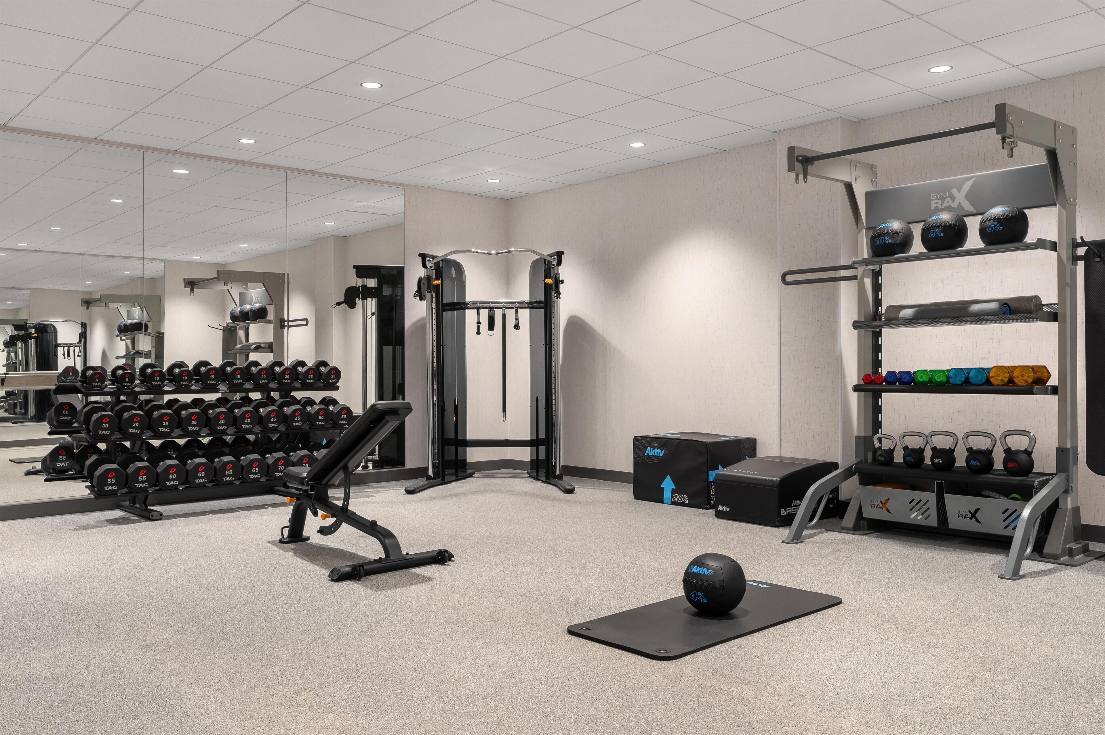 A gym with weightlifting equipment, dumbbells, and kettlebells.