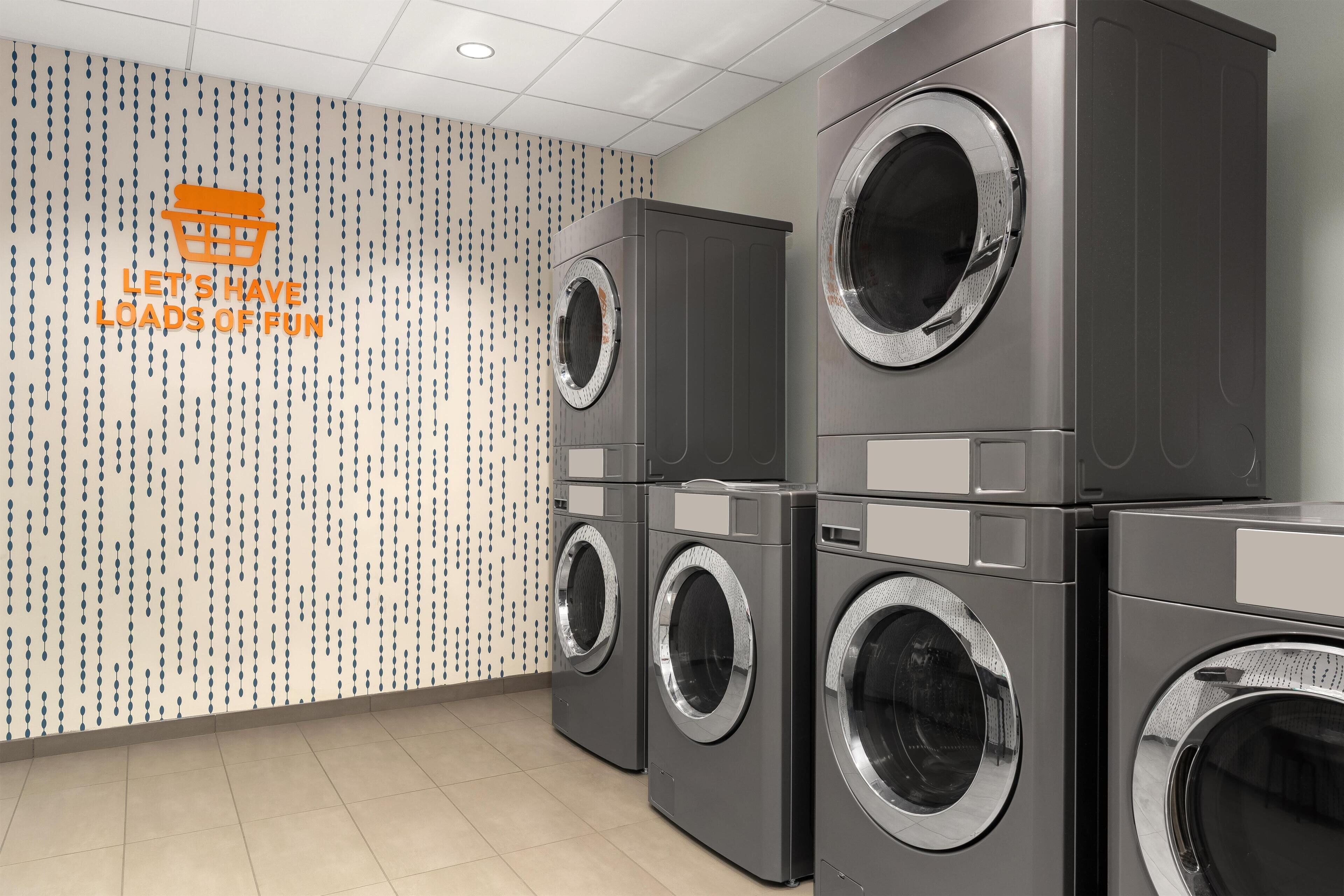 A laundry room with stacked front-loading washing machines and a patterned wall.