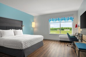 A modern hotel room with a large bed, a desk, a chair, a window with a view, and a wall-mounted TV. - Tru By Hilton Burlington, Nj (Burlington)