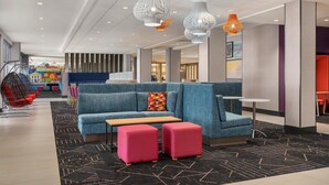 A modern lobby with a blue sofa, pink ottomans, and hanging pendant lights. - Tru By Hilton Burlington, Nj (Burlington)