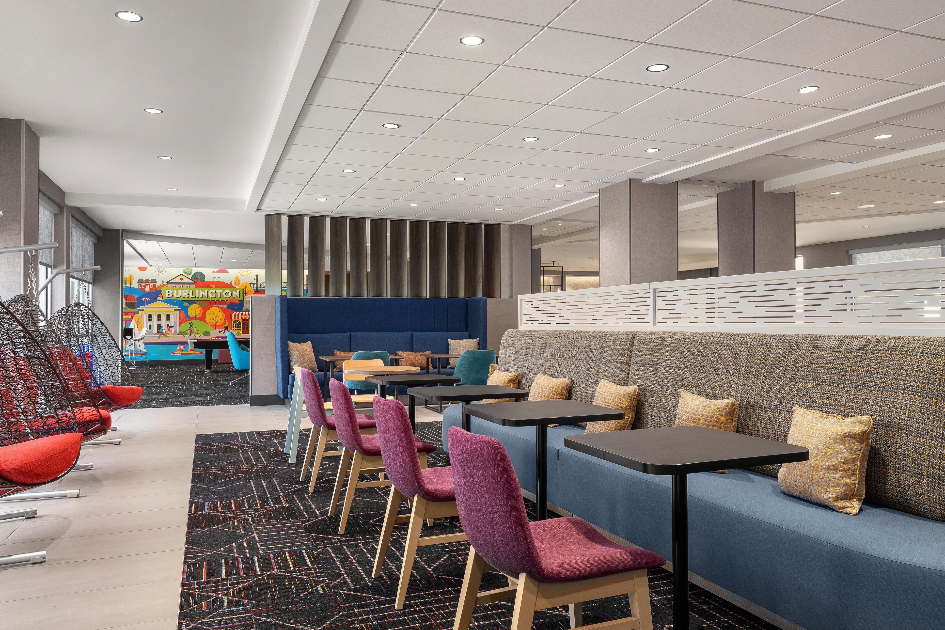 A modern hotel lobby with a blue sofa, purple chairs, and a black table.