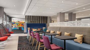 A modern hotel lobby with a blue sofa, purple chairs, and a black table.