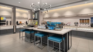 A modern kitchen area with bar stools, a coffee station, and a variety of food dispensers. - Tru By Hilton Burlington, Nj (Burlington)