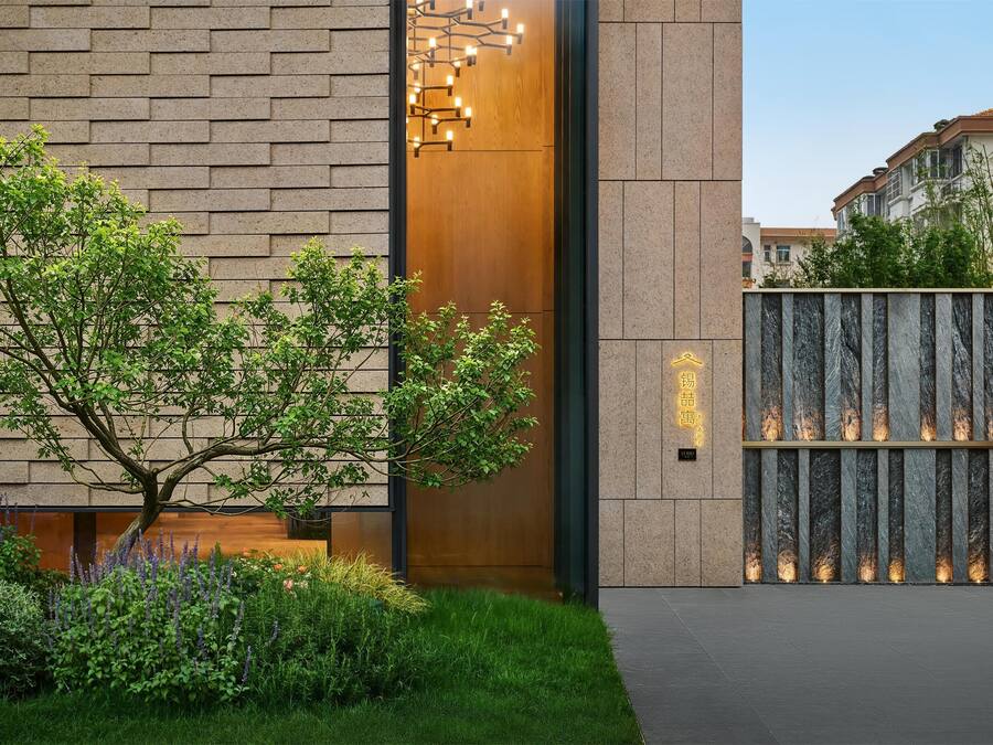 Une entrée moderne avec une porte en bois, un mur en briques et un jardin bien entretenu.