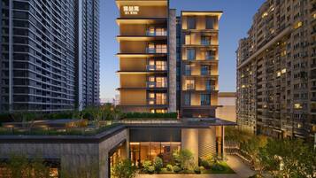 A modern multi-story building with a prominent entrance, large windows, and a rooftop garden.