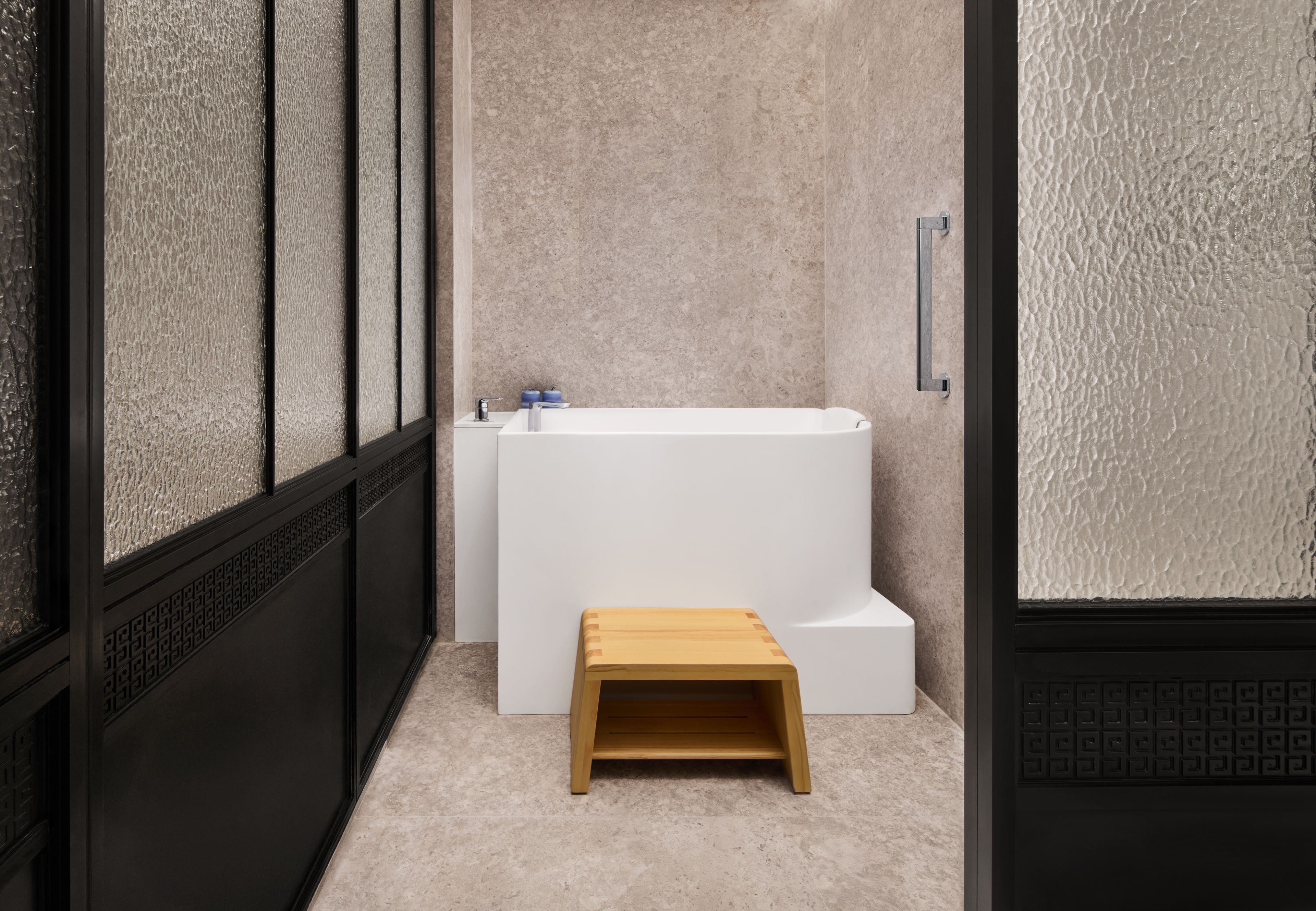 A bathroom with a bathtub, a wooden stool, and a towel rack.