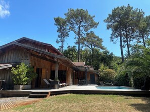 Una cabaña de madera con terraza, mobiliario exterior y piscina.