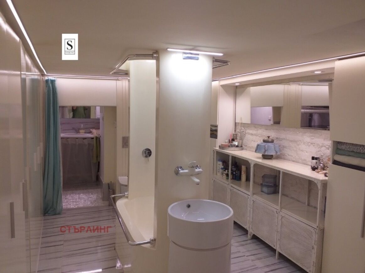 Een moderne badkamer met een groot wastafel, spiegel en opbergkasten.