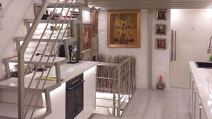 A modern kitchen with a central island, a staircase, and a mezzanine level. - Unique designer apartment in central Sofia Perfect for comfort lovers. (Sofia)