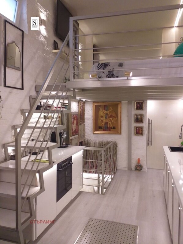 A modern kitchen with a central island, a staircase, and a mezzanine level. - Unique designer apartment in central Sofia Perfect for comfort lovers. (Sofia)