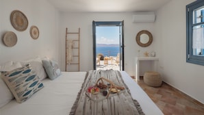 Ein Schlafzimmer mit einem Bett, einem Frühstückswagen und Blick auf das Meer.