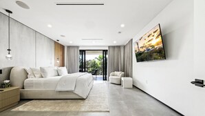 A modern bedroom with a bed, bedside table, and a large TV on the wall. - Ocean Crown Villa - A Modern Beach Getaway (Fort Lauderdale)