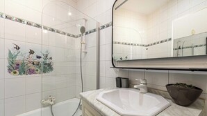 Un bagno con una vasca, un lavandino, uno specchio e piastrelle decorative.