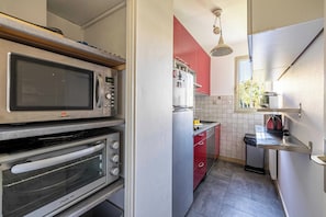 A compact kitchen with a microwave, oven, and refrigerator. - Bright Apartment with Terrace and Sea View (Cannes)