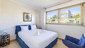 Una camera da letto con un letto, una sedia, una finestra e un quadro appeso al muro.