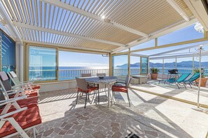 A sunlit outdoor area with a table and chairs, a view of the sea, and potted plants. - Bright Apartment with Terrace and Sea View (Cannes)