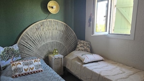 A bedroom with a bed, a bedside table, a window, and a wall-mounted fan. - The yellow house (Vidauban)