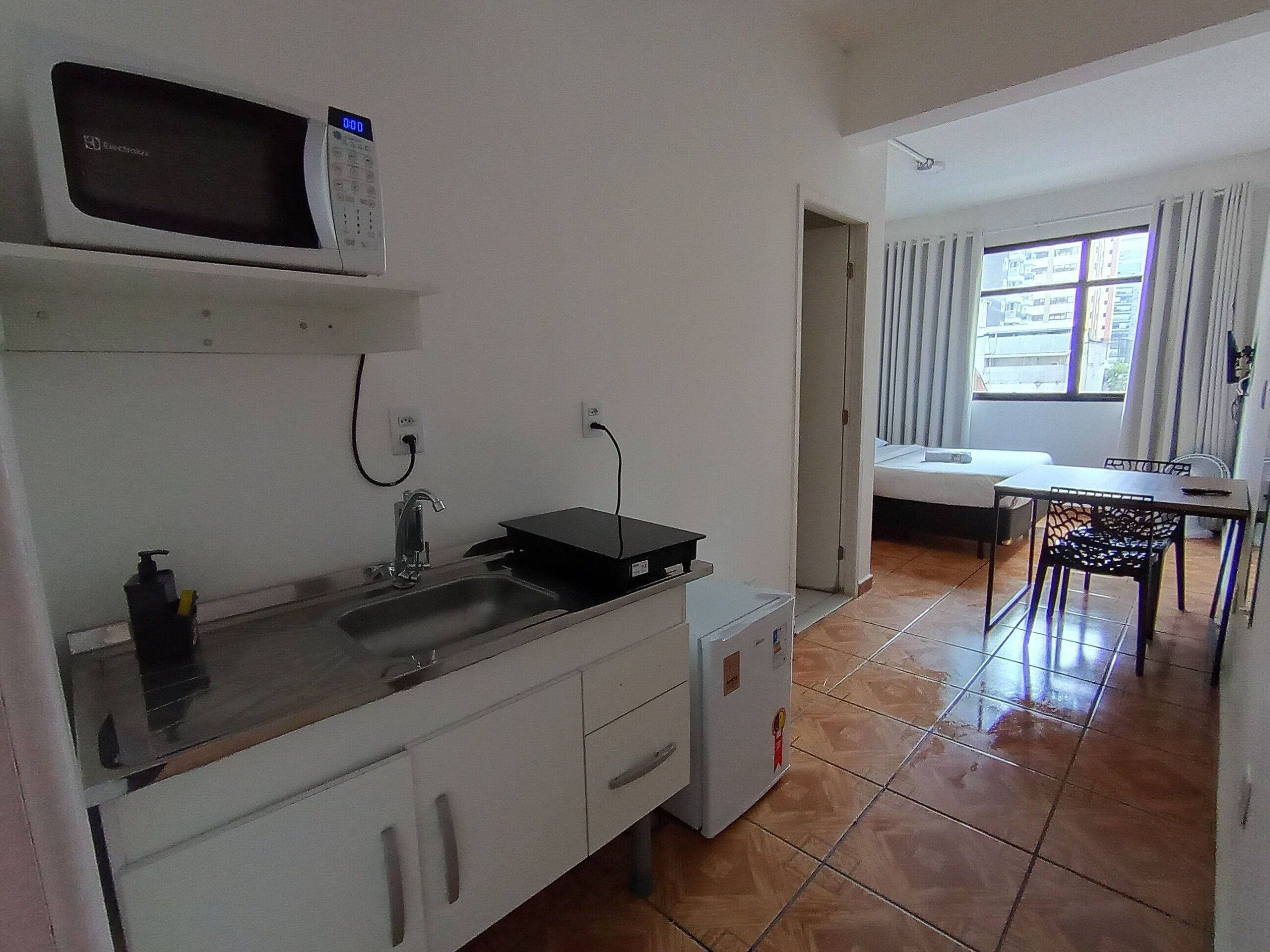 A small kitchenette with a microwave, sink, and a compact refrigerator.
