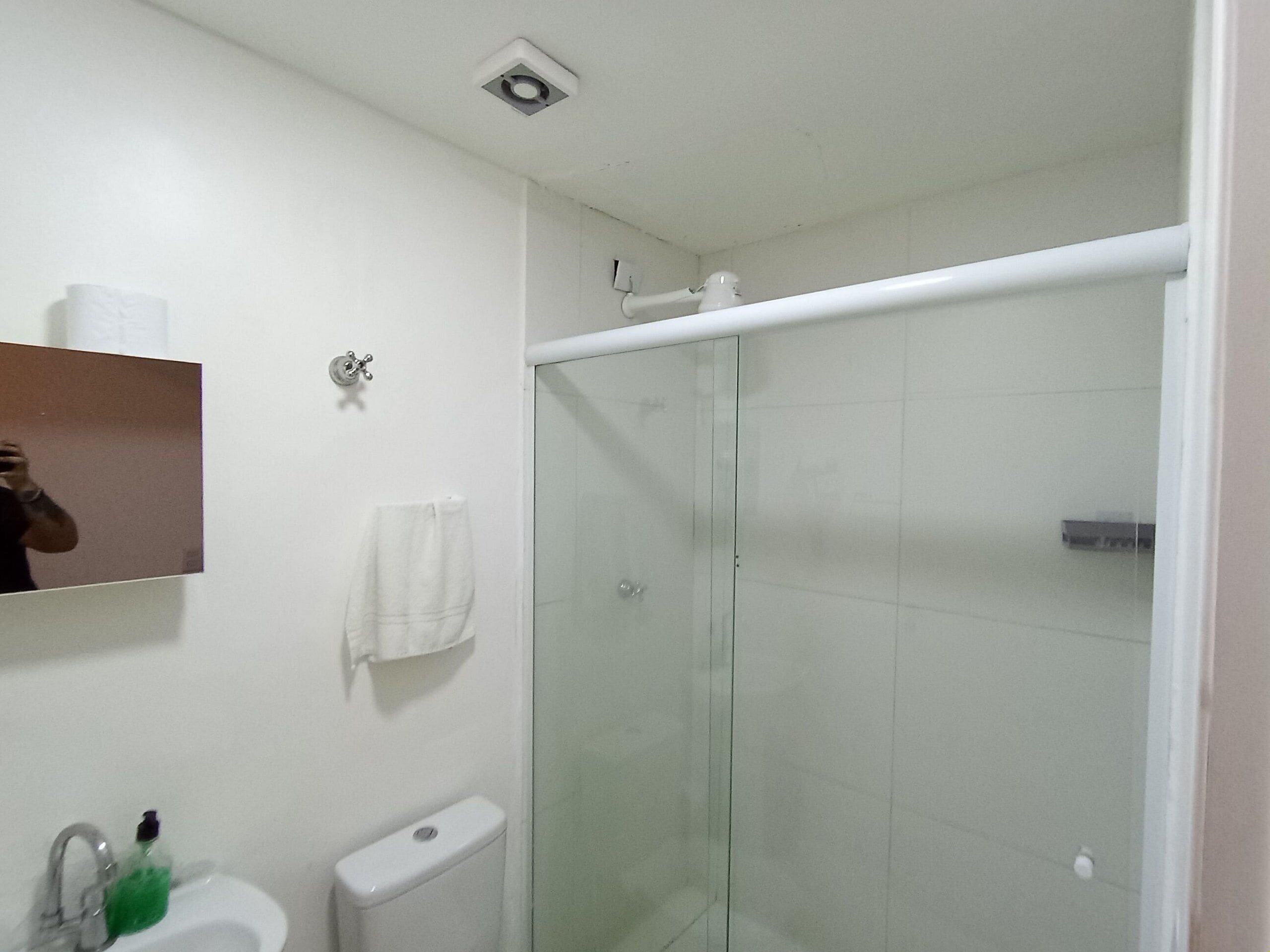 A bathroom with a glass-enclosed shower, a sink with a mirror, and a toilet.