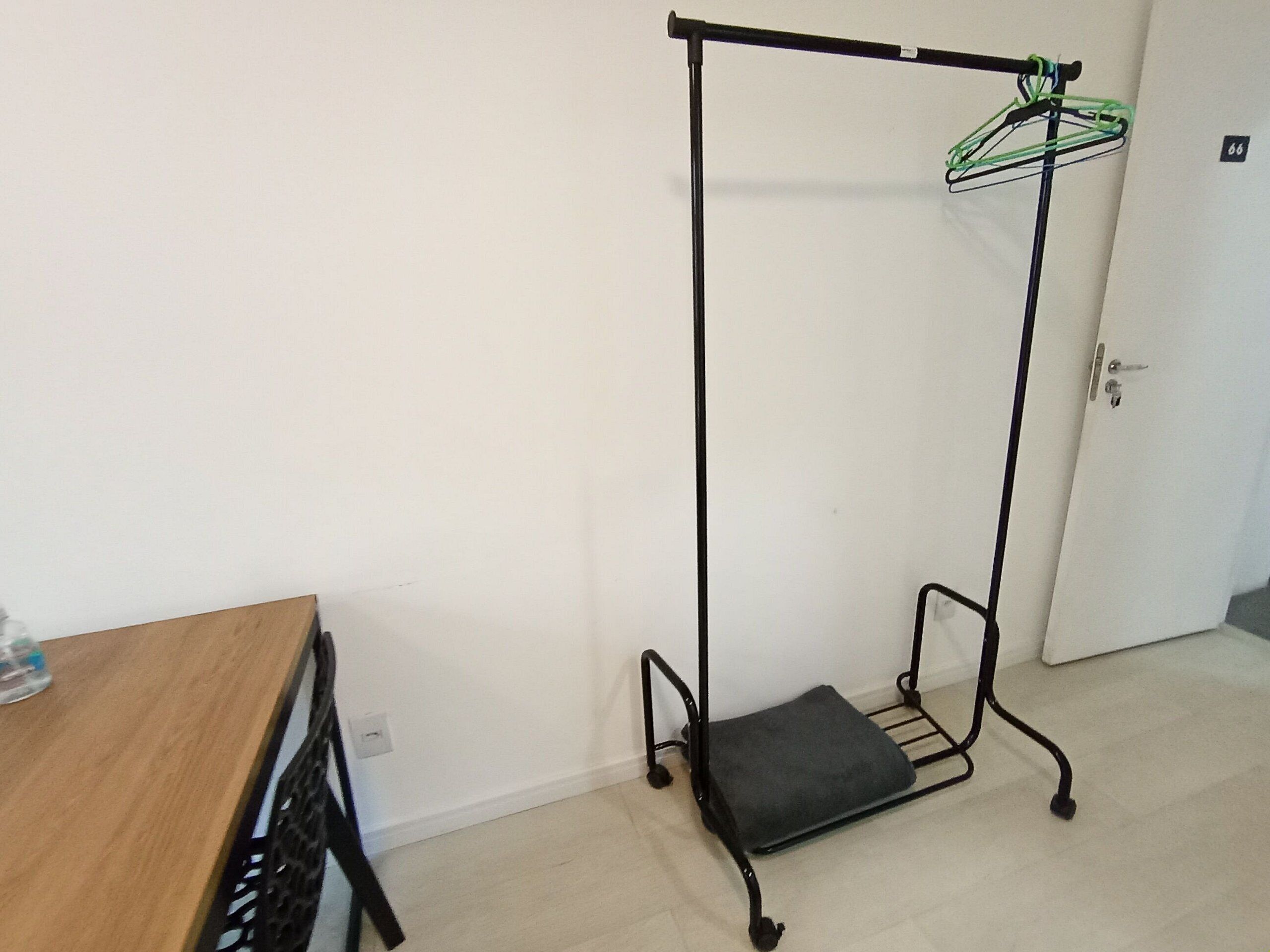 A room with a wooden table, a black metal rack with a cushion, and a white door.