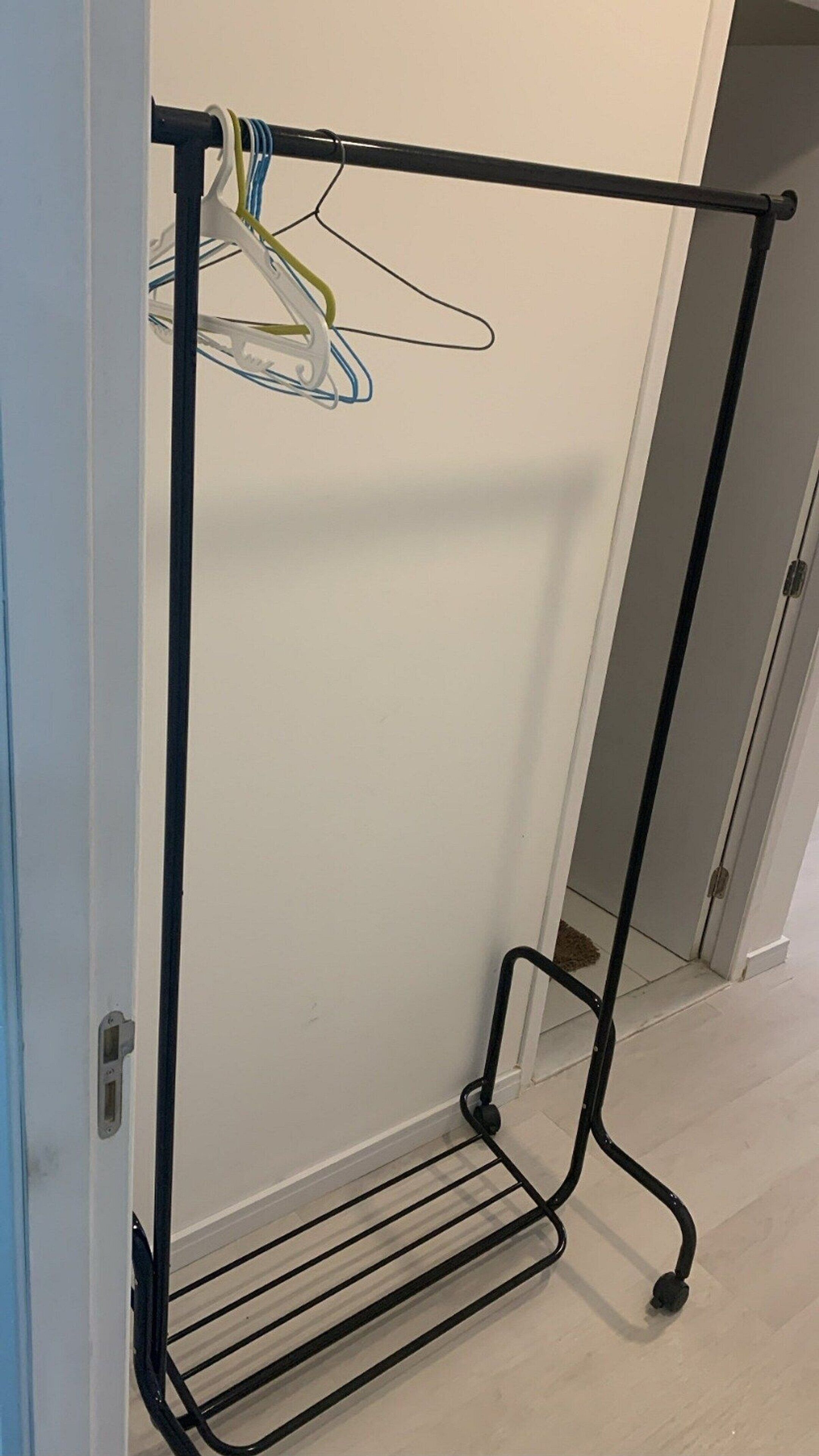 A metal rack with shelves and a hanging bar, likely used for storing clothes.