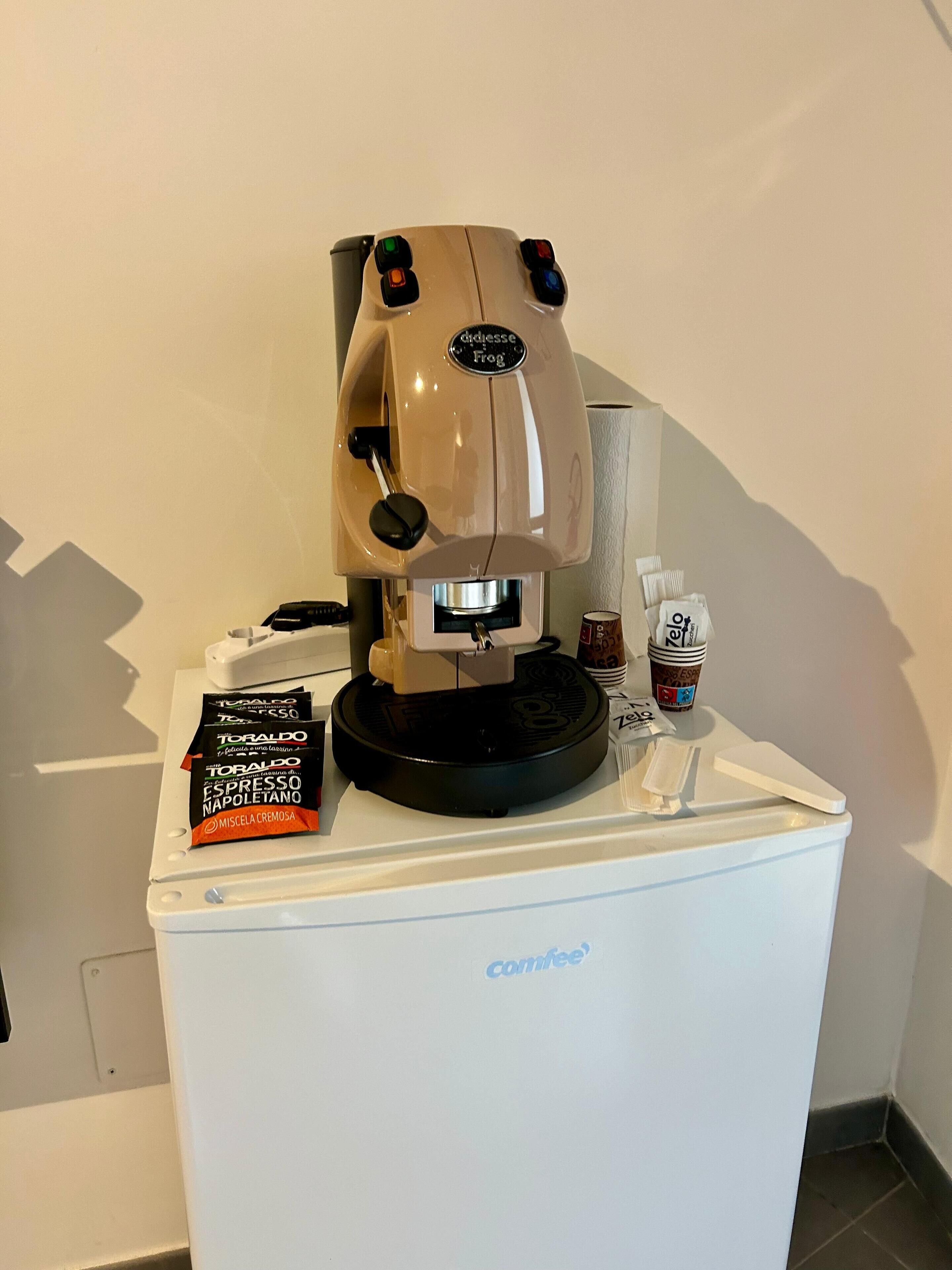 Une machine à café sur un comptoir blanc, avec une dosette de café et une tasse de café.
