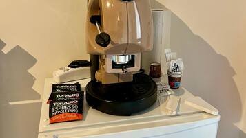 Une machine à café sur un comptoir blanc, avec une dosette de café et une tasse de café.
