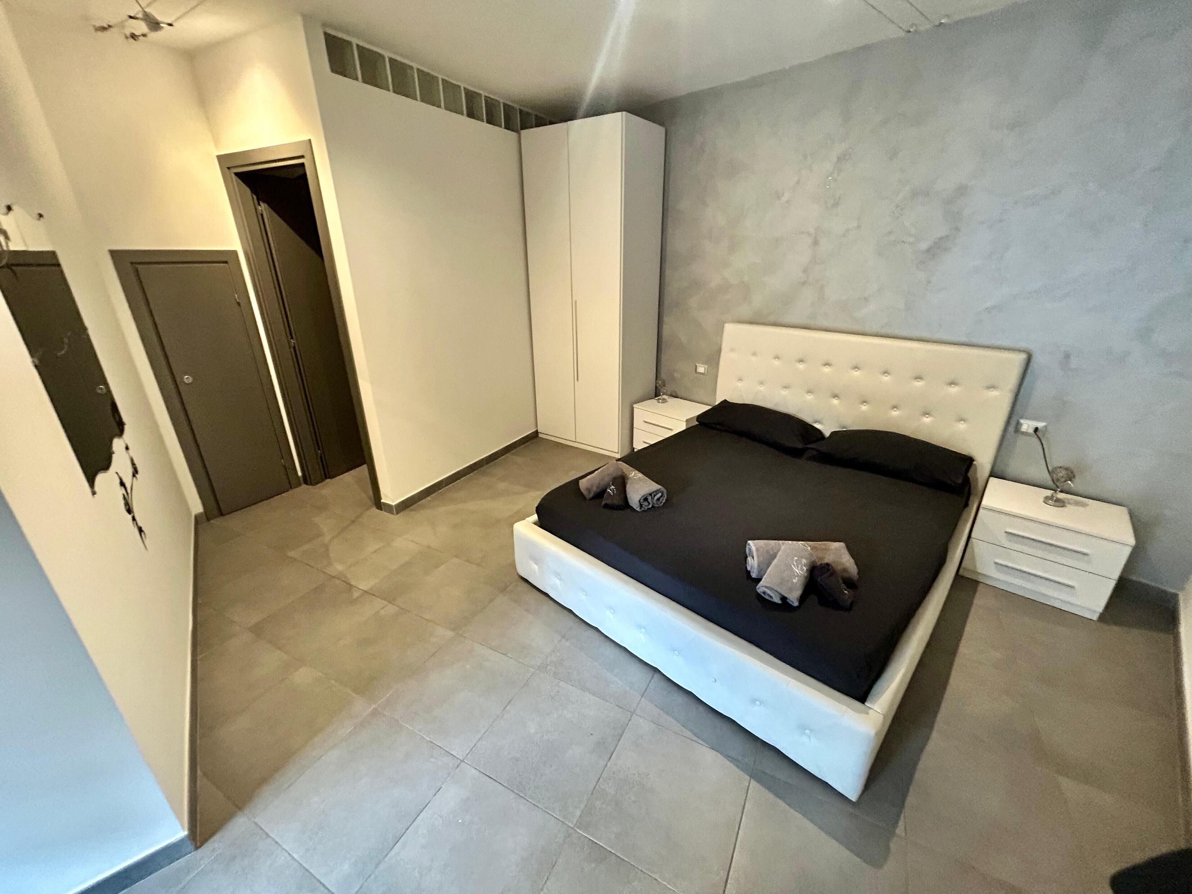 Un dormitorio con una cama grande, un armario y una mesita de noche.
