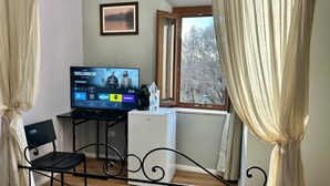 A room with a TV displaying 'Fratelli Demoliti' on Prime Video, a coffee maker, a bottle of water, a chair, and a window with curtains. - Ninfa del Lago Bedrooms  (Posta Fibreno)