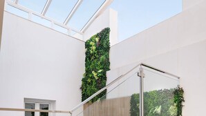 Un escalier moderne avec des rampes en verre et un mur végétal vertical.