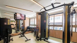 A gym with various exercise equipment, a television, and large windows. - Fully Equipped Accommodations in a Building With a Pool, 270m From Barra Beach - Caoa (Salvador)