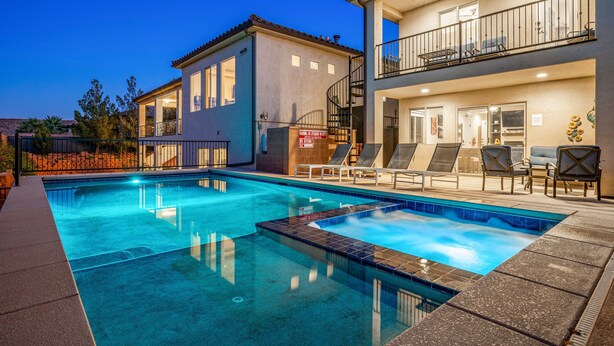 Une piscine avec des chaises longues et une maison à deux étages dotée de balcons.