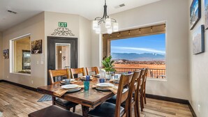 Un coin repas avec une table dressée pour quatre personnes, une vue sur un paysage désertique et un panneau indiquant la sortie sur le mur.