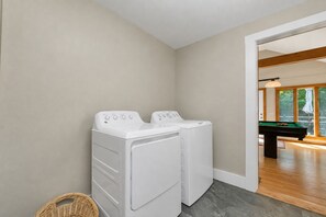 A laundry room with two white washing machines and a wooden pool table in the background. - Quaint Bethel Home with Firepit - Walk to Town (Bethel)