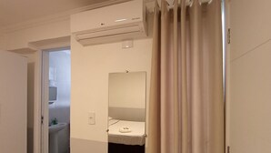 A hotel room with a bed, a mirror, an air conditioning unit, and a bathroom visible through an open door. - WeStay Budget-Unidade 3 (São Paulo)