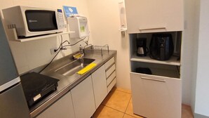 A compact kitchenette with a microwave, coffee maker, and a small sink. - WeStay Budget-Unidade 3 (São Paulo)